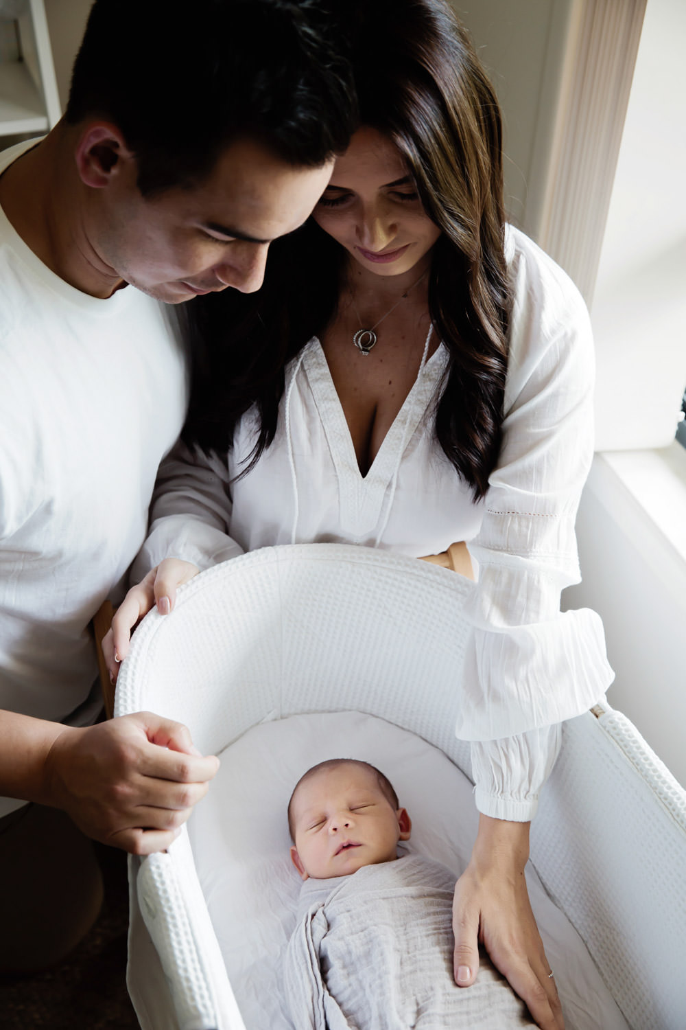 parents-looking-into-newborn-babies-bassinet- natural_Family-Photography-Packages_Beach_Brisbane-GoldCoast